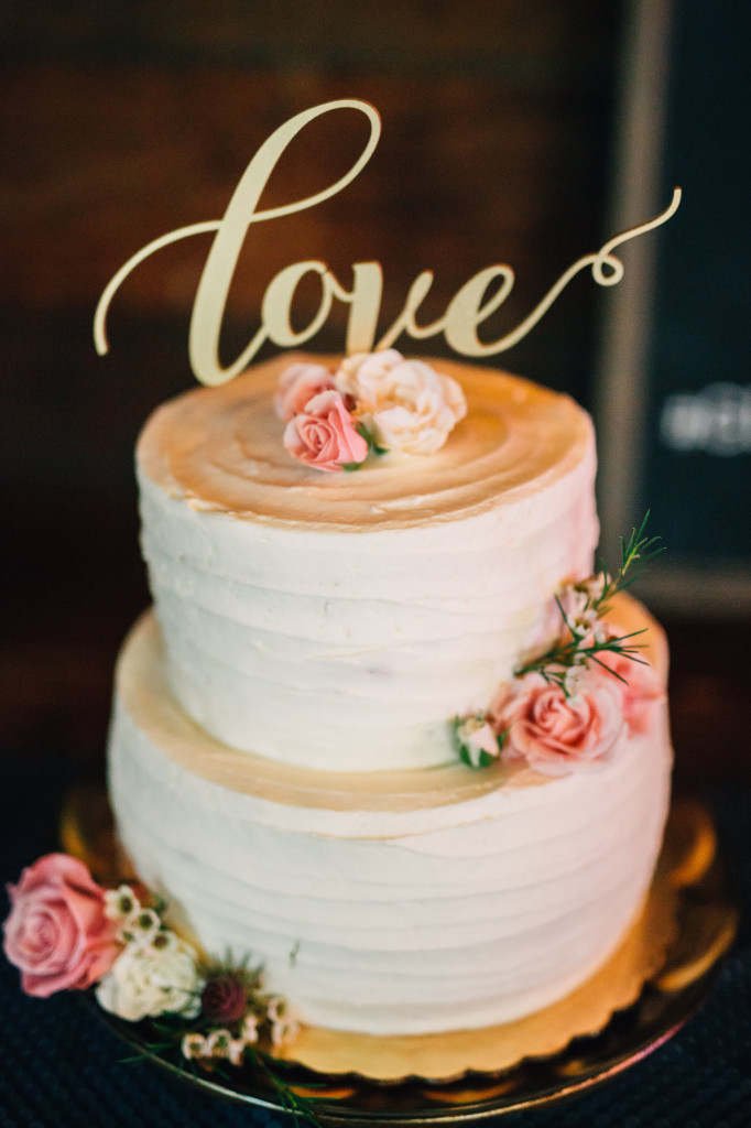 Simple tiered white wedding cake with gold love cake topper and pink flowers | EntertainingLife.com
