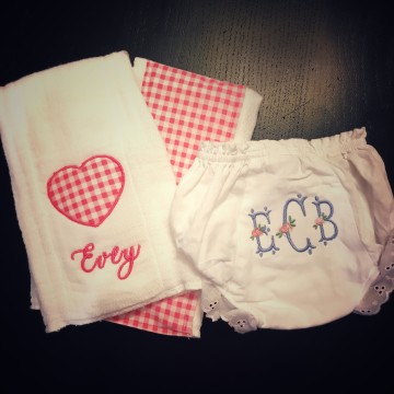 A set of coordinated embroidered burp cloths and diaper covers.